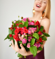 Beautiful woman hold bouquet of red and pink roses flowers happy smiling on grey 