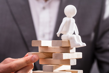 Human Figure Sitting On Top Of Stacked Wooden Blocks