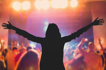 Silhouette of a girl with arms wide open on the concert.