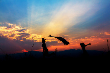 Silhouette children playing at sunset background