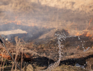 A man extinguishes the burning grass with water