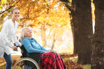 Disabled senior woman and young nurse in park