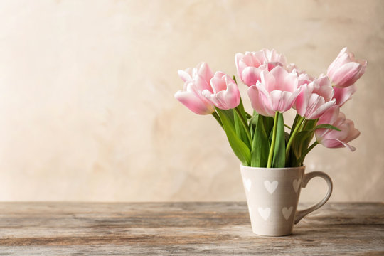 Cup with beautiful tulips for Mother's Day on table