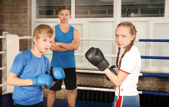 Little boy and girl fighting on boxing ring