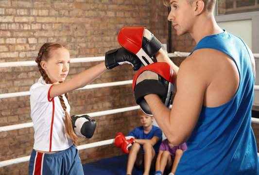 Little girl with trainer on boxing ring