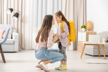 Young mother helping her daughter get ready for school
