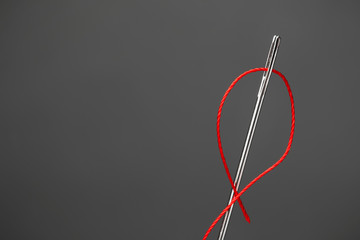 Needle with sewing thread on dark background, closeup