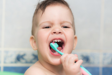 lovely baby brushing his teeth with a toothbrush in the bathroom