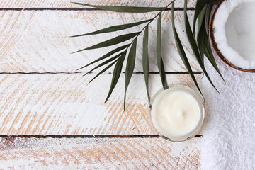 Obraz na płótnie Canvas Cosmetic natural skin care products from coconut. palm leaf, coconut and cosmetic cream on a wooden background. minimalism, the top. flatlay 