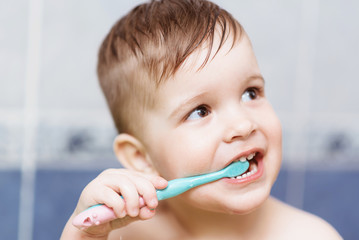 lovely baby brushing his teeth with a toothbrush in the bathroom