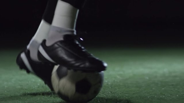 Closeup of feet of professional male soccer player training with ball on stadium field with artificial turf