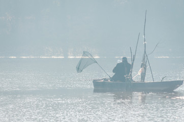 Fisherman in a wooden boat on the lake 