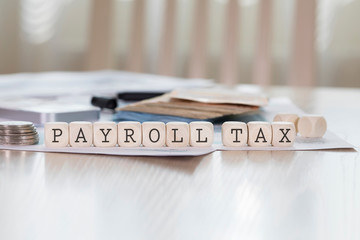 Word PAYROLL TAX is composed of wooden letters.