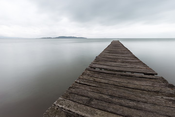 Long exposure first person view of a pier on a lake with perfectly still water