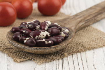 Beans in a wooden spoon on old wooden table.