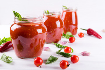 Fototapeta na wymiar Tomato sauce, ketchup in glass jar and ingredients on a white background