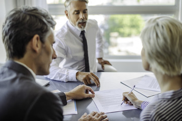 Woman signing document in meeting with business professionals