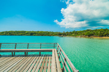 Fototapeta na wymiar Wooden pier or bridge with tropical beach and sea in paradise island