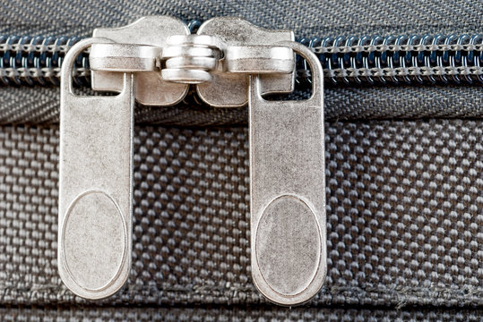 Close-up Two Zipper Runners Buttoned Up On A Gray Suitcase