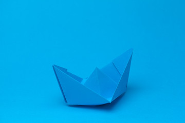 Origami paper boat on blue background
