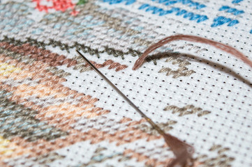 Cross stitch embroidery process with brown cotton thread in the needle