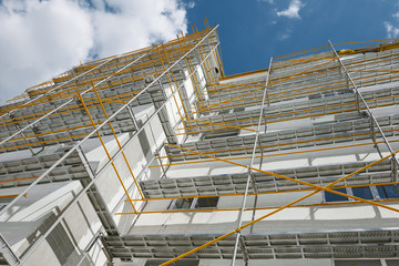 scaffolding near a new house, building exterior, construction and repair industry, white wall and window, yellow pipe