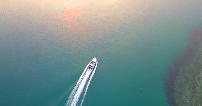 Aerial 4K: Tourist Motor boat passing water channel at sunset time