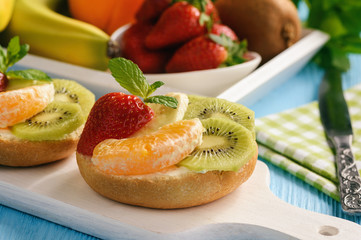 Healthy breakfast fruits and ricotta sandwiches- with strawberries, kiwi and orange.