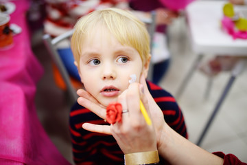 Face painting for cute little boy during kids birthday party