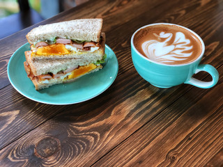Fresh sandwich and swan shape Latte art coffee cup on the wooden table. Delicious Breakfast , Natural Light and copy space