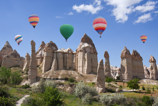Unique geological formations and colorful hot air balloons flying over Love valley in Cappadocia, Turkey