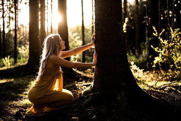 Junge Frau betet im Wald zum Sonnenuntergang