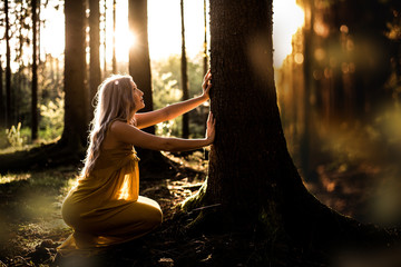 Junge Frau betet im Wald zum Sonnenuntergang