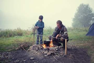 Father and son on the river by the fire.