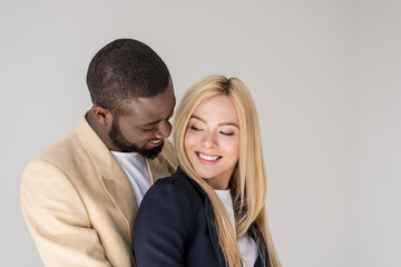 portrait of beautiful happy young multiethnic couple posing together isolated on grey