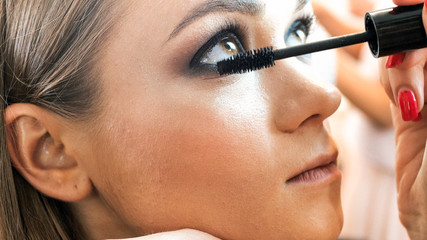 Closeup image of makeup artist applying mascara on eyelashes
