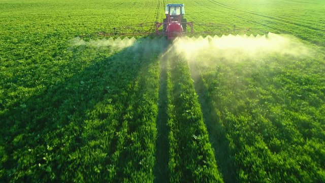 Aerial view of farming tractor plowing and spraying on field