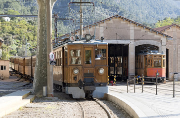 Soller Station, Mallorca, Spain. April 2018. Electric locomotive pulling train from Palma arrives in Soller. An electric tram is in a shed