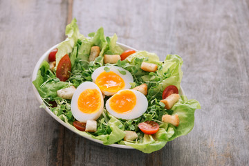 High Angle View of a Nutritious Vegetable Salad with Boiled Egg Slices, Served on a White Plate on Top of a Wooden Table