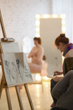 Artists sketching a nude model in drawing class