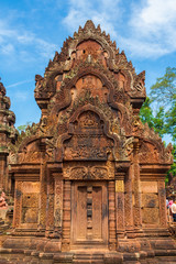 Fototapeta na wymiar The facade of the north library in Cambodia's Banteay Srei (Citadel of the Women) temple. The pediment has a detailed bas-relief, depicting the scene of Indra dousing the fire at the Khandava forest.