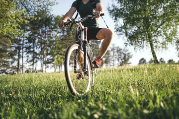 Fototapeta na wymiar Cyclist man feet riding mountain bike on outdoor trail deep grass