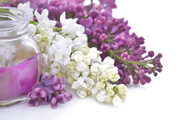 Obraz na płótnie Canvas Glass candle among flowers of pink and white lilac on white background