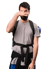 Fototapeta na wymiar Handsome backpacker making smelling bad gesture on white background