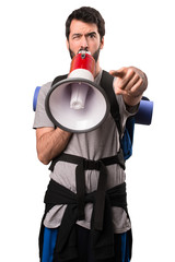 Handsome backpacker holding a megaphone on white background