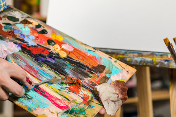 Obraz premium the hand of a man with a brush on the canvas. art, creativity, hobby and people