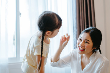 Mother feeding snack to daughter eating in the morning at home side window funny family together lifestyle.