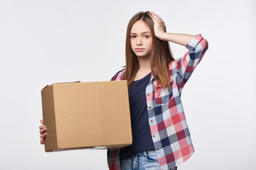 Delivery, relocation and unpacking problems. Discontent young woman holding cardboard box with hand...