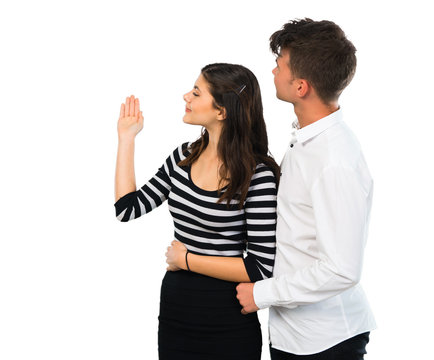 Young couple pointing back with the index finger on isolated white background