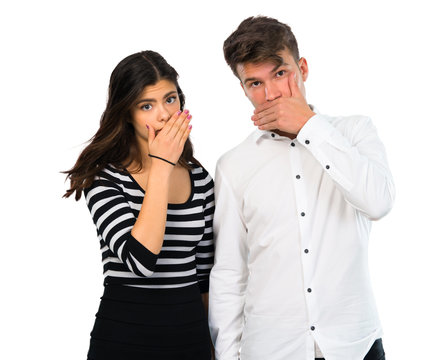 Young couple covering mouth with hands on isolated white background